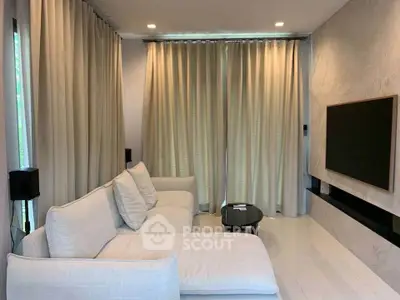 Modern living room with elegant white sofa and large TV, featuring floor-to-ceiling curtains.