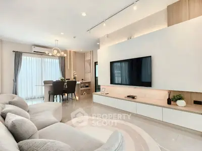 Spacious modern living room with elegant decor and large TV, perfect for relaxation and entertainment.