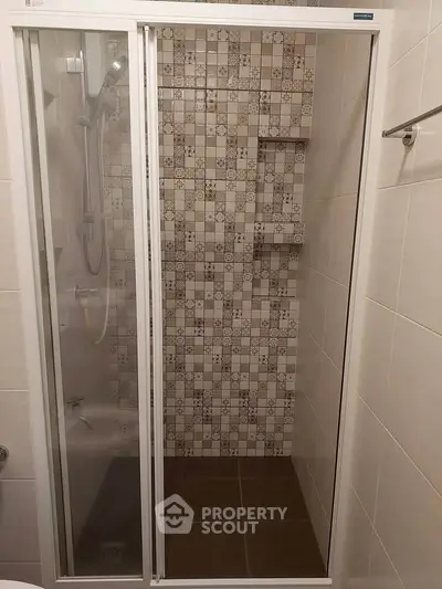 Modern bathroom with stylish tiled shower and glass door enclosure.
