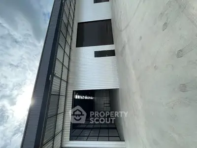 Modern industrial building exterior with sleek metal facade and large windows.