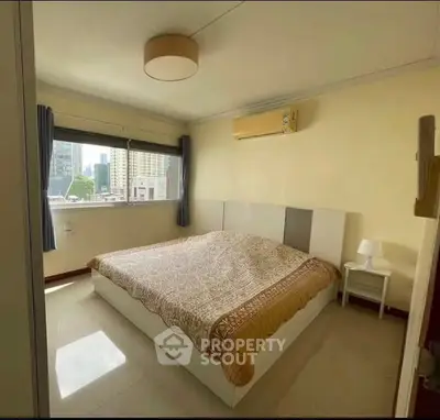 Cozy bedroom with city view, featuring a large window, modern bed, and air conditioning.