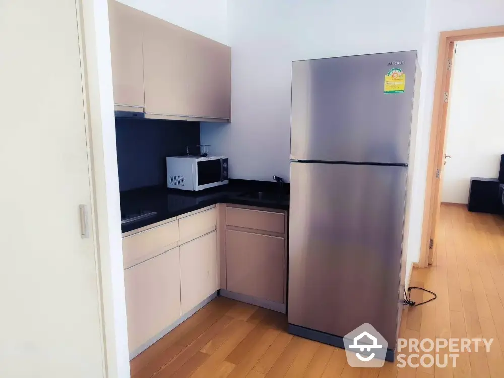 Modern kitchen with sleek stainless steel fridge and microwave in compact layout