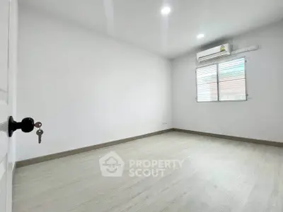 Spacious empty room with wooden flooring and air conditioning, perfect for customization.