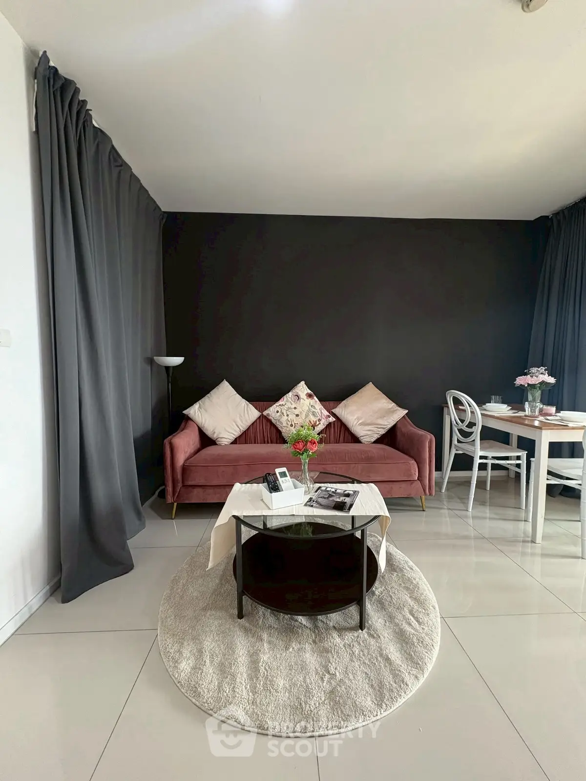 Stylish living room with modern decor, featuring a cozy pink sofa and elegant dining area.