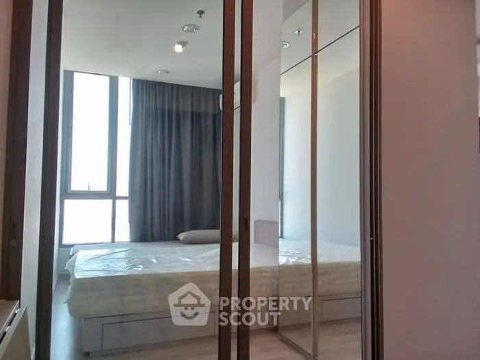 Modern bedroom with large windows and mirrored closet doors in a stylish apartment.