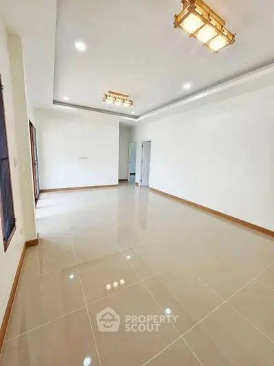 Spacious and bright empty living room with modern lighting and glossy tiled flooring.
