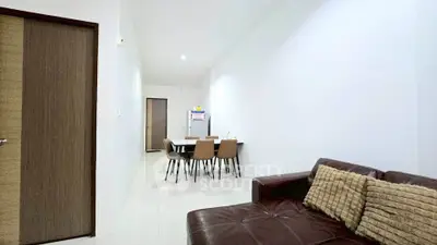 Modern living room with sleek furniture and dining area in a minimalist apartment.