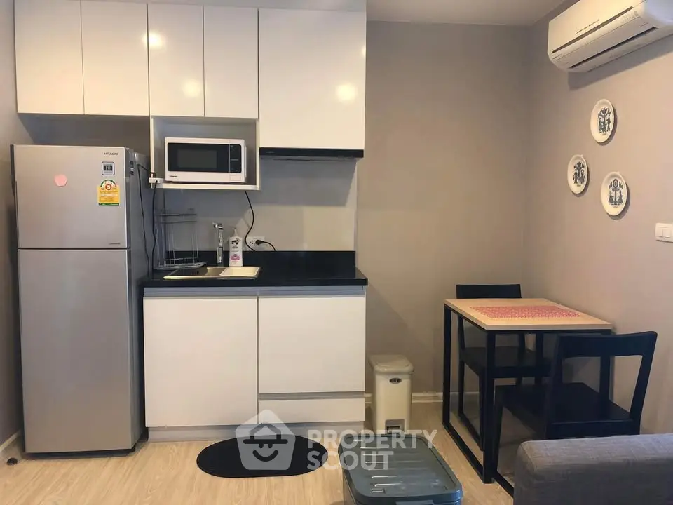 Modern compact kitchen with dining area, featuring sleek cabinetry and stainless steel appliances.
