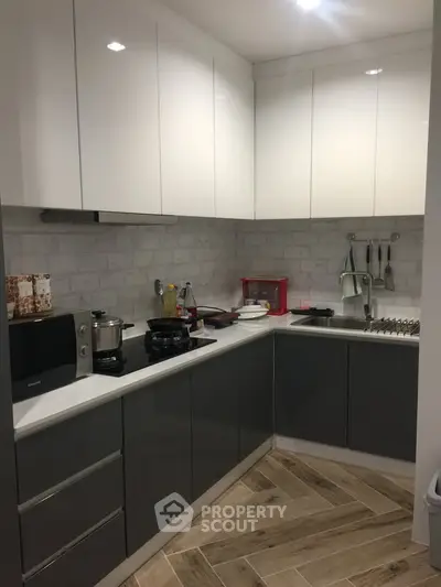 Modern kitchen with sleek cabinetry and stylish backsplash in a cozy corner layout.