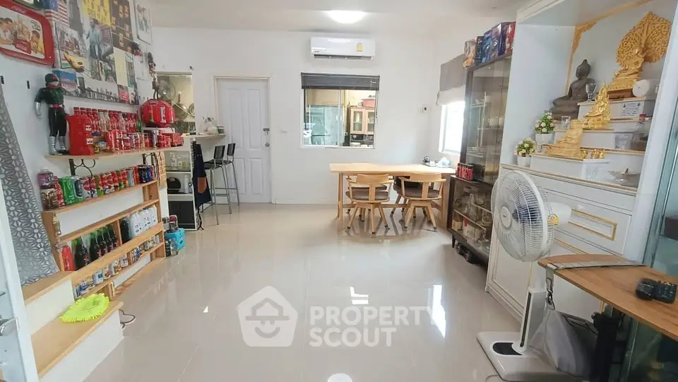 Spacious living room with modern decor and ample natural light, featuring a cozy dining area and stylish shelving.