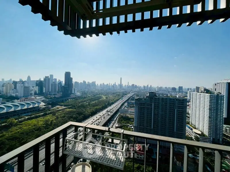 Stunning cityscape view from a high-rise balcony with expansive skyline and lush greenery.