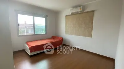 Spacious bedroom with wooden flooring and large window for natural light.