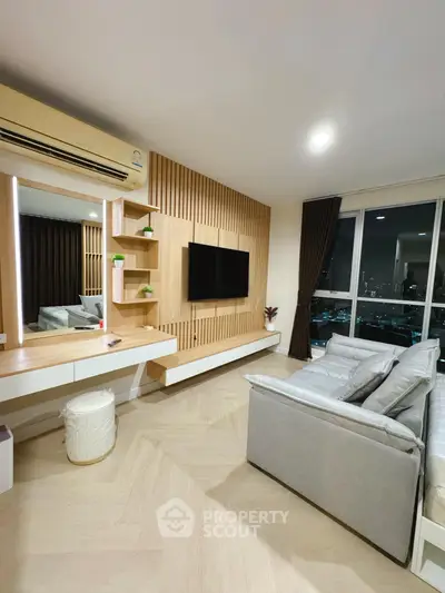 Modern living room with city view, featuring sleek design and cozy seating area.
