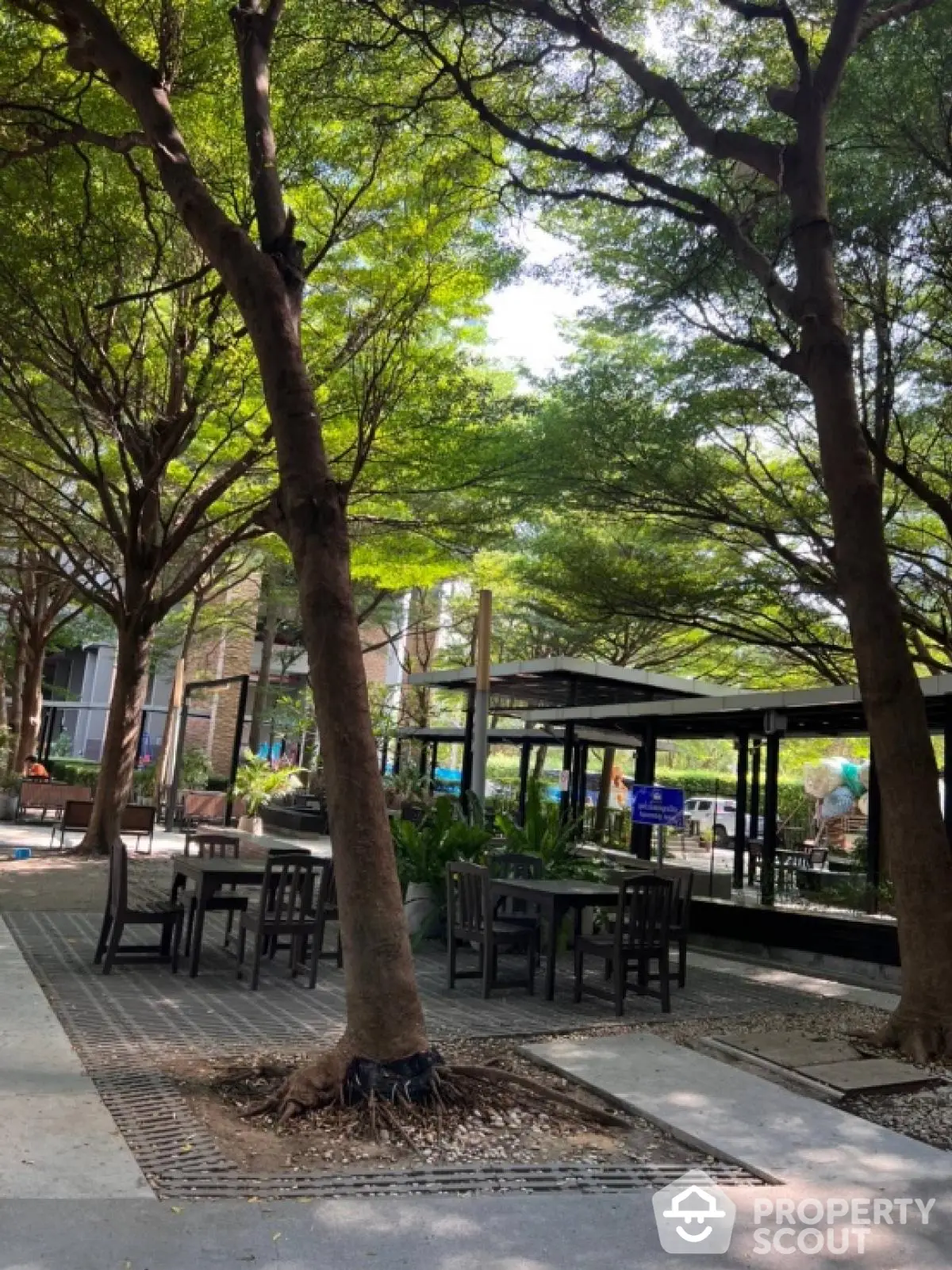 Serene garden area with outdoor seating and lush trees in a modern residential complex.