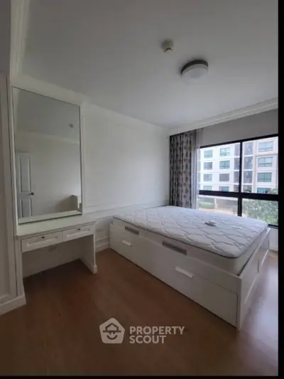 Spacious bedroom with large window and built-in vanity in modern apartment