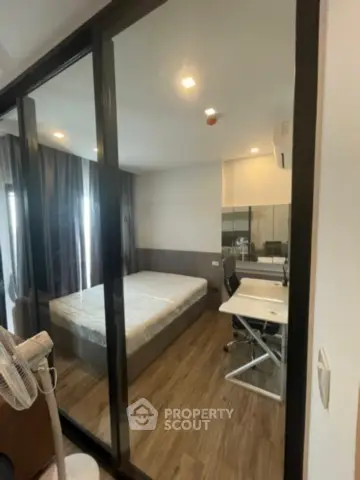 Modern bedroom with glass partition and study area, featuring sleek design and natural light.