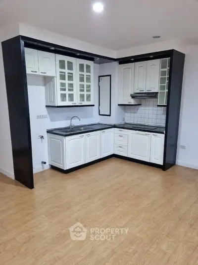 Modern kitchen with sleek cabinetry and wood flooring in a stylish apartment