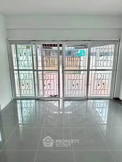 Spacious room with large windows and glossy tiled floor, perfect for natural light lovers.