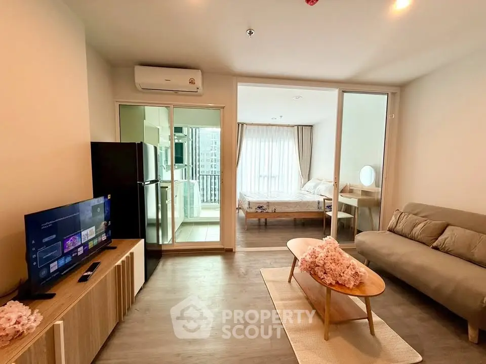 Modern open-plan living room with cozy sofa, TV, and view into stylish bedroom.