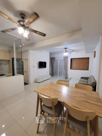 Modern open-plan living room with dining area and ceiling fans, featuring sleek furniture and bright lighting.