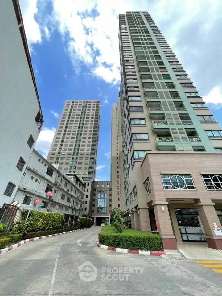 Modern high-rise residential building with clear blue sky and lush greenery.