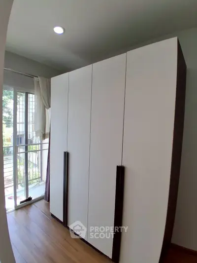 Spacious bedroom with large wardrobe and natural light from window