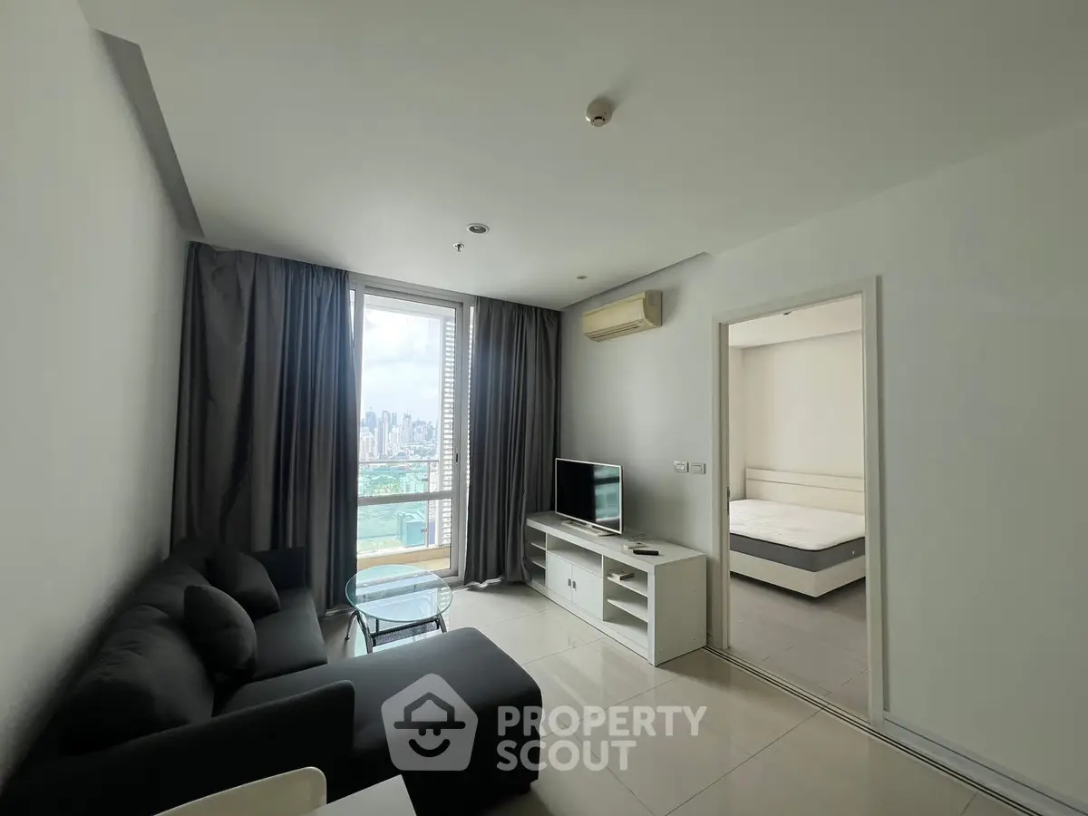 Modern living room with city view, sleek furniture, and adjacent bedroom in a stylish apartment.