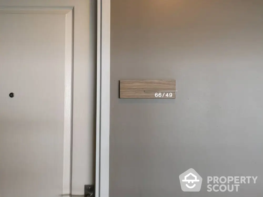 Modern apartment entrance with sleek door and unit number sign on wall.