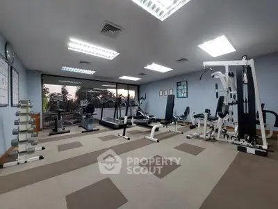 Spacious gym with modern equipment and large windows offering a scenic view.