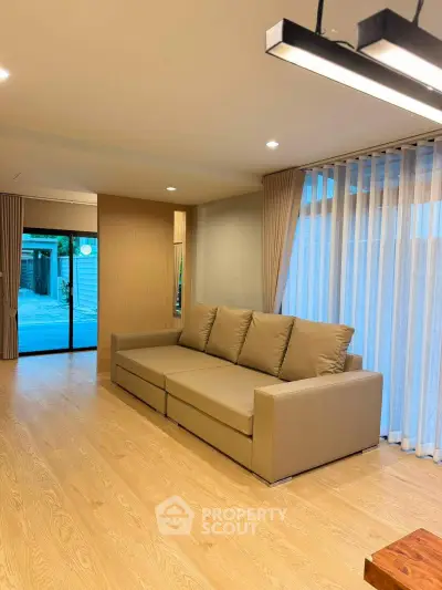 Spacious modern living room with elegant sofa and large windows for natural light.