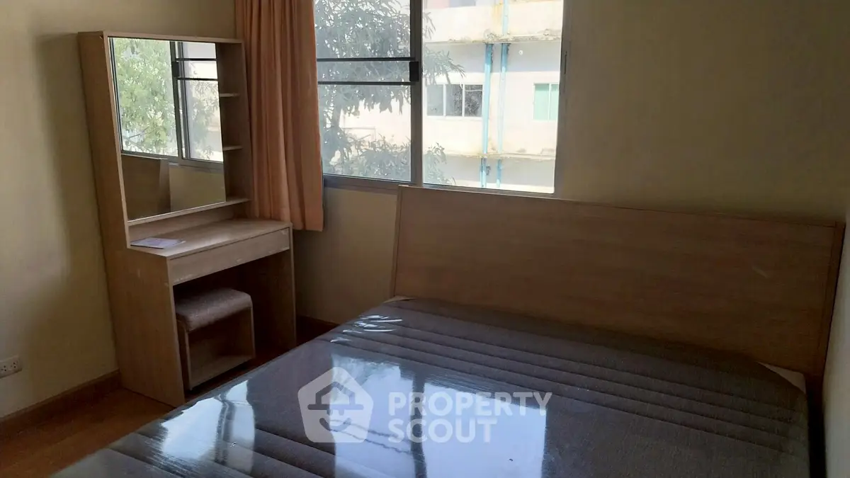 Cozy bedroom with large window and wooden furniture, perfect for natural light lovers.