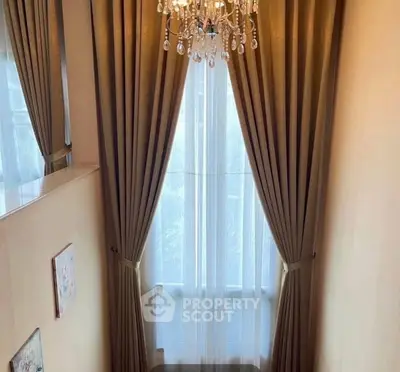 Elegant interior with chandelier and floor-to-ceiling drapes in a cozy living space.