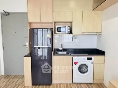 Modern compact kitchen with appliances including fridge, microwave, and washing machine.