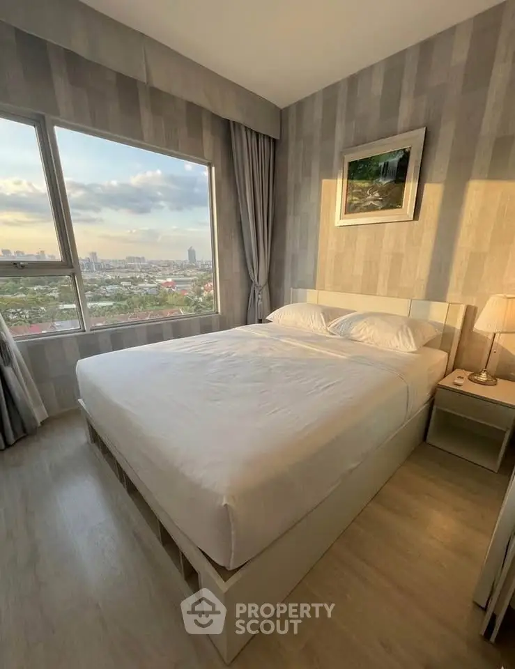 Cozy bedroom with city view, featuring a large window and modern decor, perfect for relaxation.