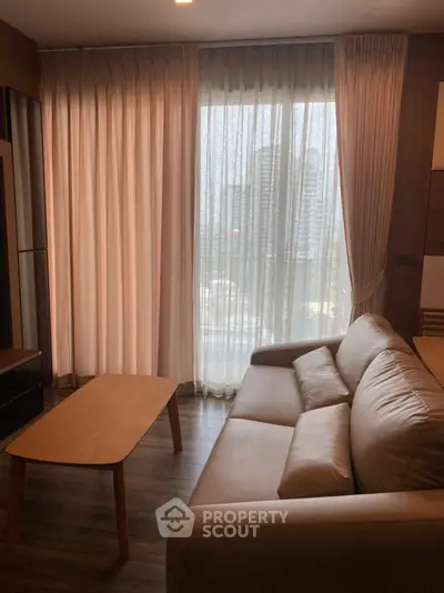 Cozy living room with modern furniture and large window offering city view.