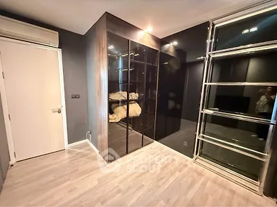 Modern bedroom with sleek glass wardrobe and wooden flooring