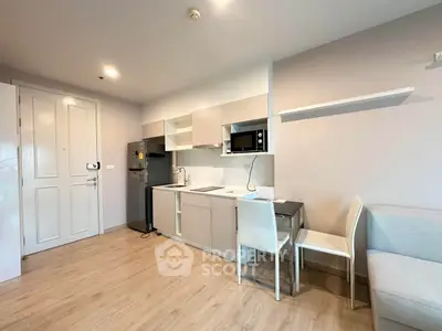 Modern kitchen with sleek cabinetry, microwave, and dining area in a stylish apartment.
