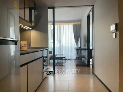 Modern open-layout kitchen leading to a bright living room with floor-to-ceiling windows.