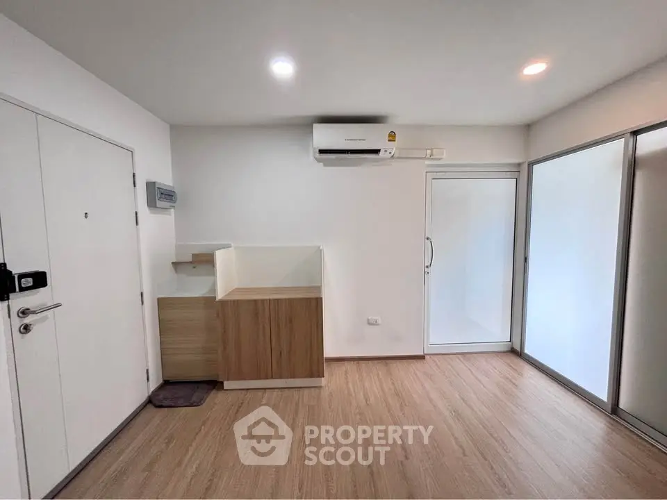 Modern minimalist interior with wooden flooring and air conditioning in a compact living space.