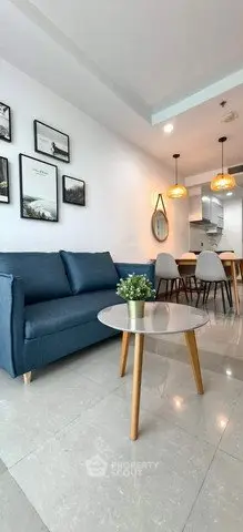 Modern living room with blue sofa, stylish decor, and open kitchen layout