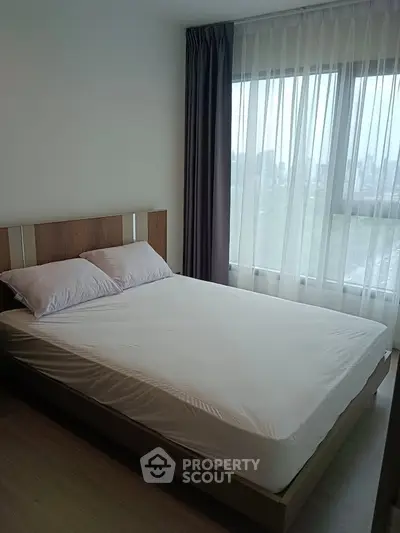 Modern bedroom with large window and natural light in a stylish apartment.