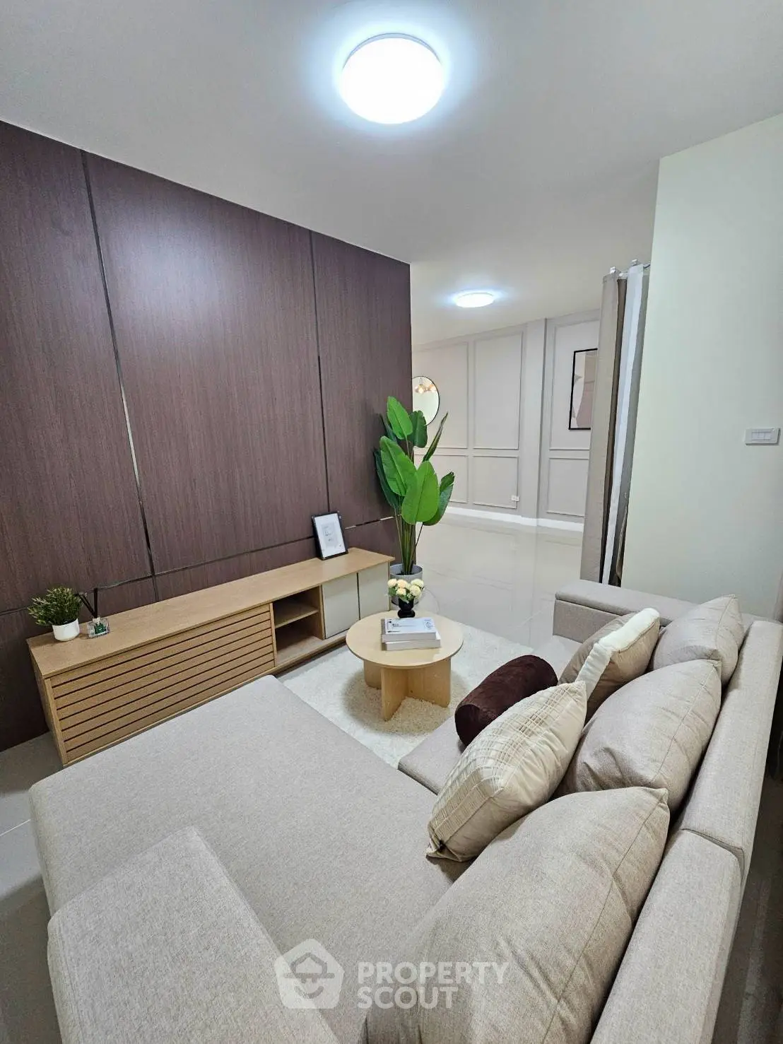 Modern living room with cozy beige sofa, stylish wooden paneling, and elegant decor for a welcoming ambiance.