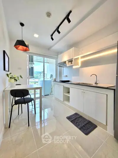 Modern kitchen with sleek white cabinets and open layout, featuring a cozy dining area and bright natural light.