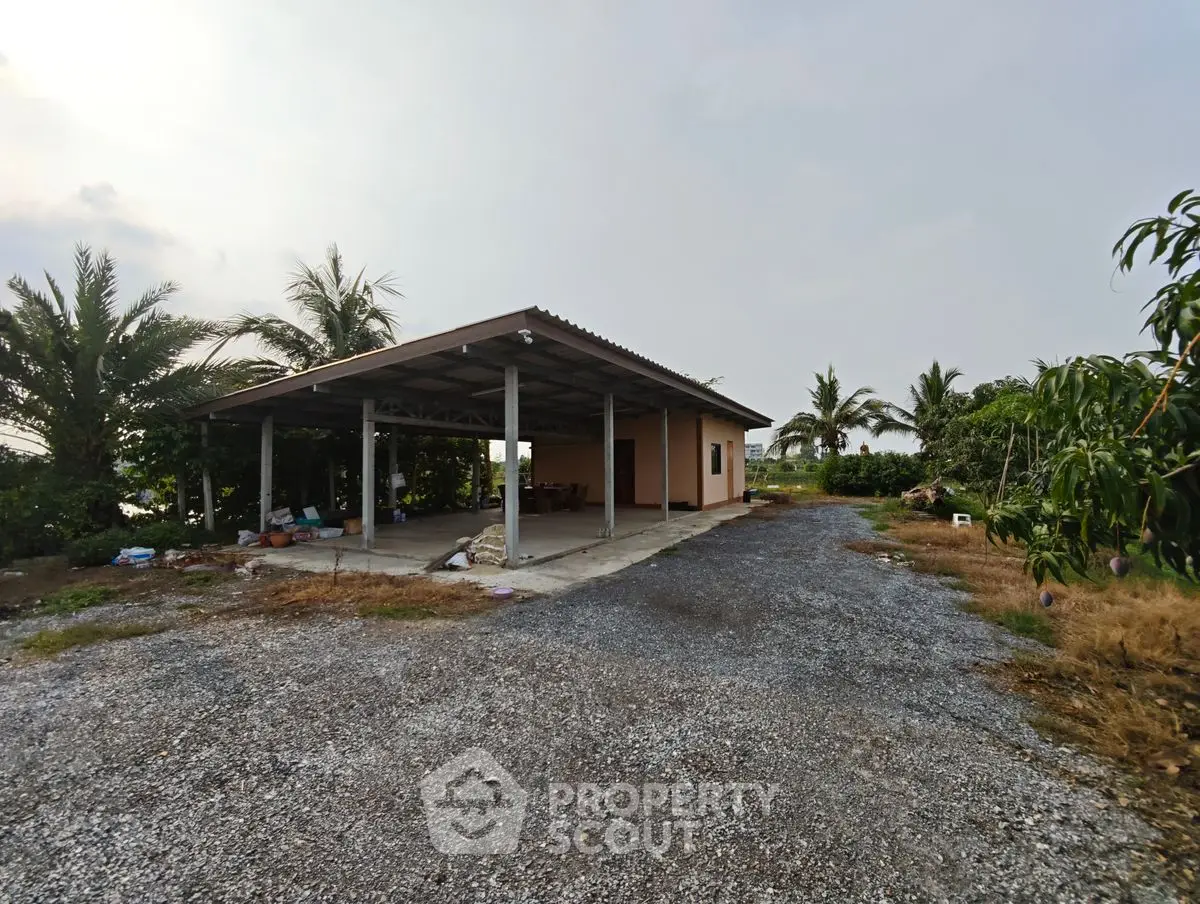 Spacious rural property with open garage and lush greenery, ideal for development or farming.