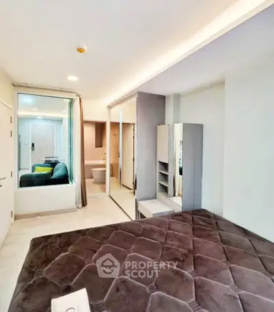 Modern bedroom with mirrored wardrobe and cozy seating area in a stylish apartment.