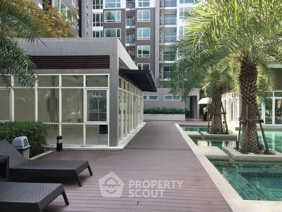 Modern apartment complex with poolside view and lush greenery