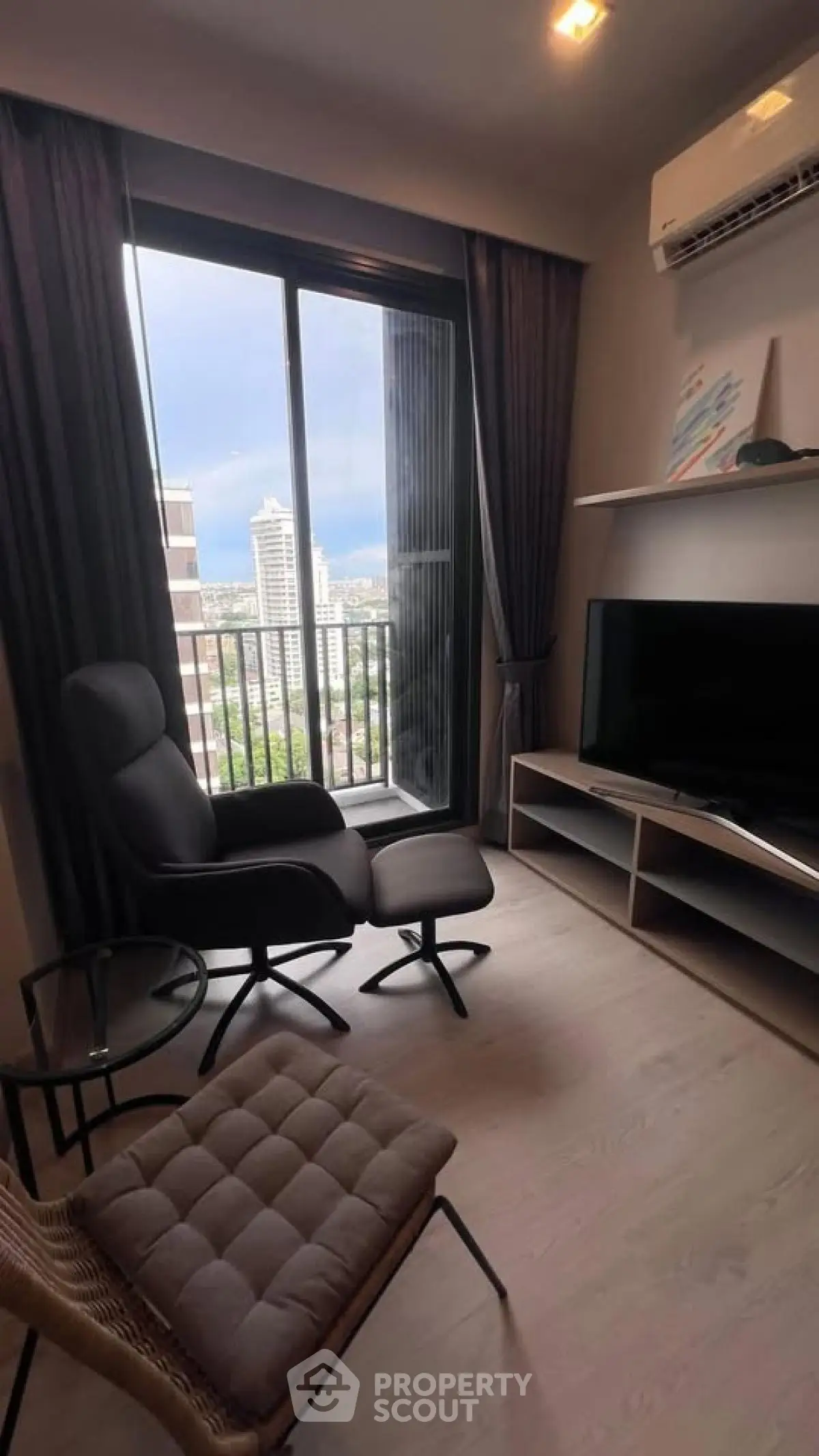 Modern living room with city view, featuring sleek furniture and large window for natural light.