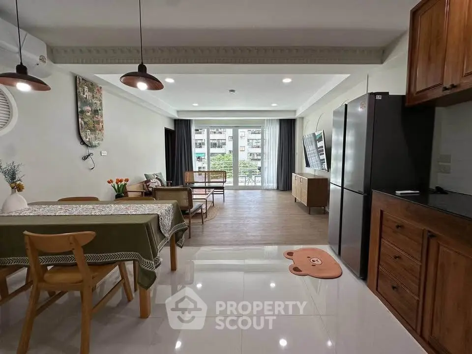 Spacious open-plan living and dining area with modern kitchen and balcony view.