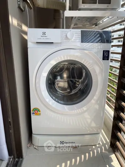Modern Electrolux washing machine on a balcony with city view, perfect for urban living convenience.