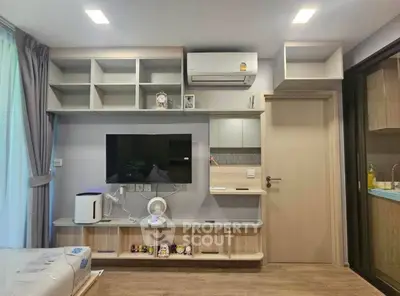 Modern living room with built-in shelves, air conditioning, and sleek TV setup in a cozy apartment.